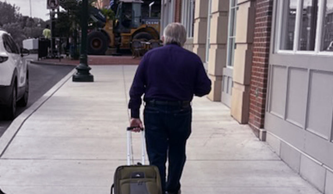 Jim Shore walking pulling luggage