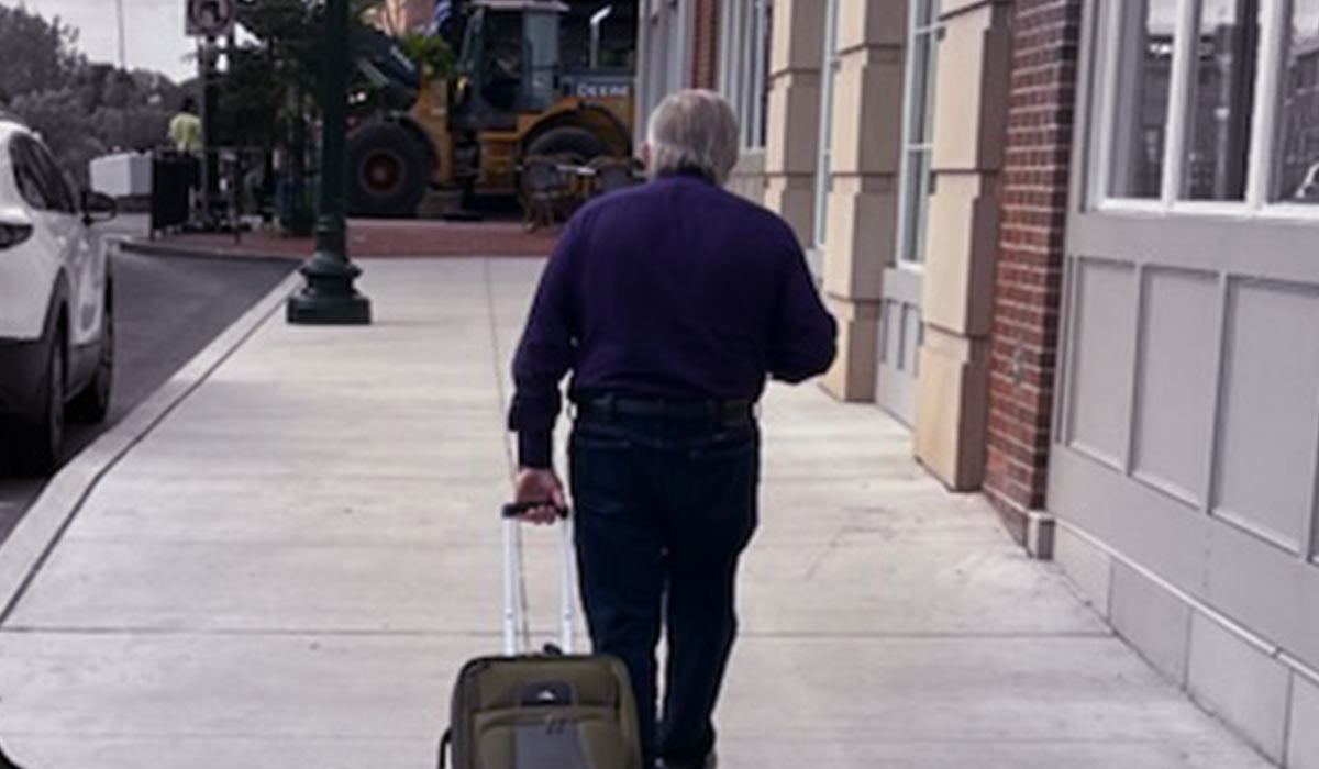 Jim Shore walking pulling luggage