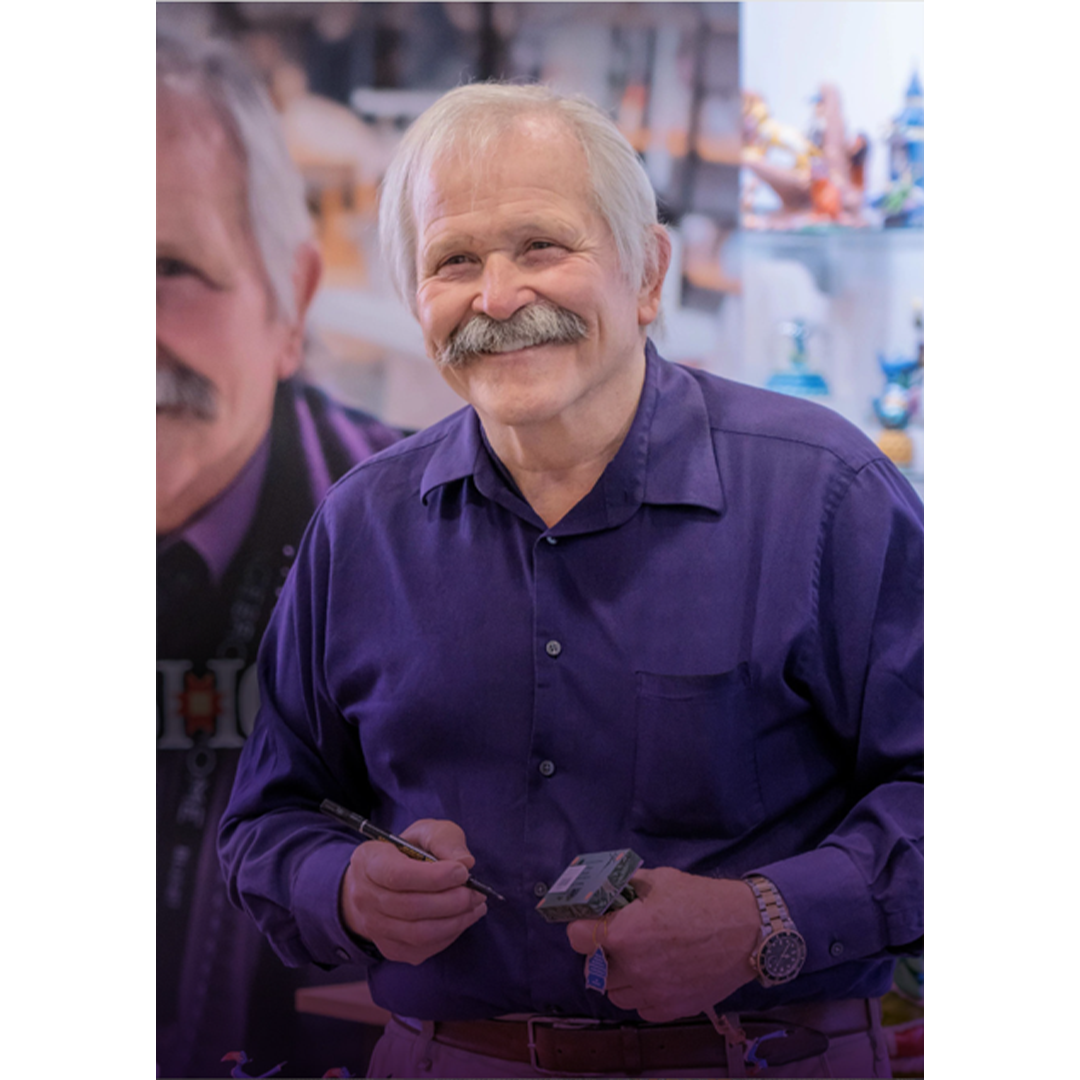 Jim in a purple shirt holding a tool against a blurred background