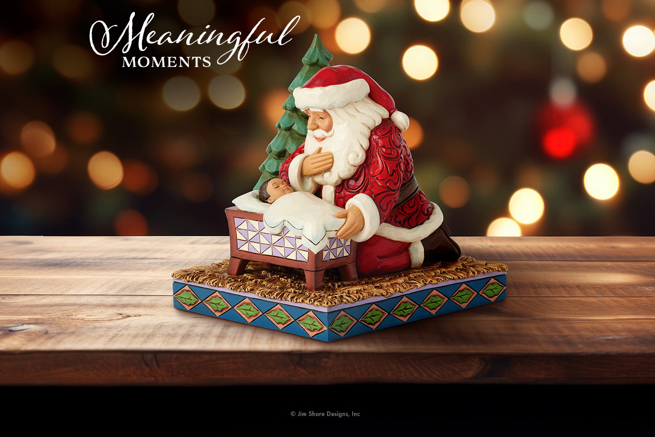 Decorative figurine of Santa Claus with a tree on a wooden platform, blurred lights in the background.