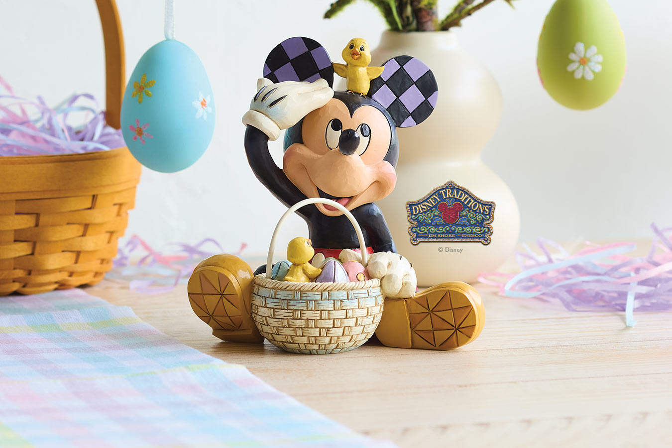 Disney figurine of a character with Easter eggs and a basket on a table.