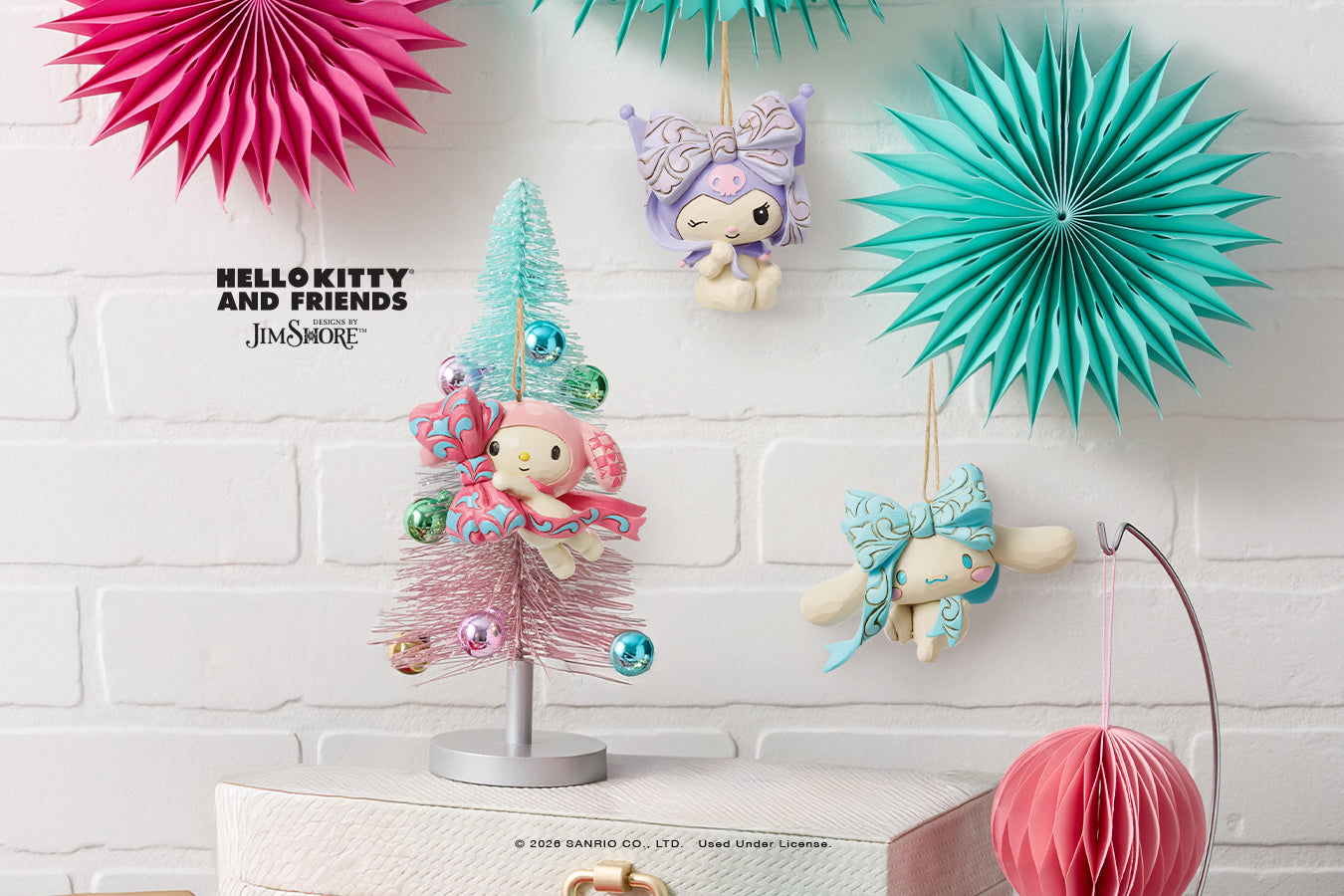 Decorative items including a small Christmas tree, hanging figures, and paper fans on a white brick wall background.