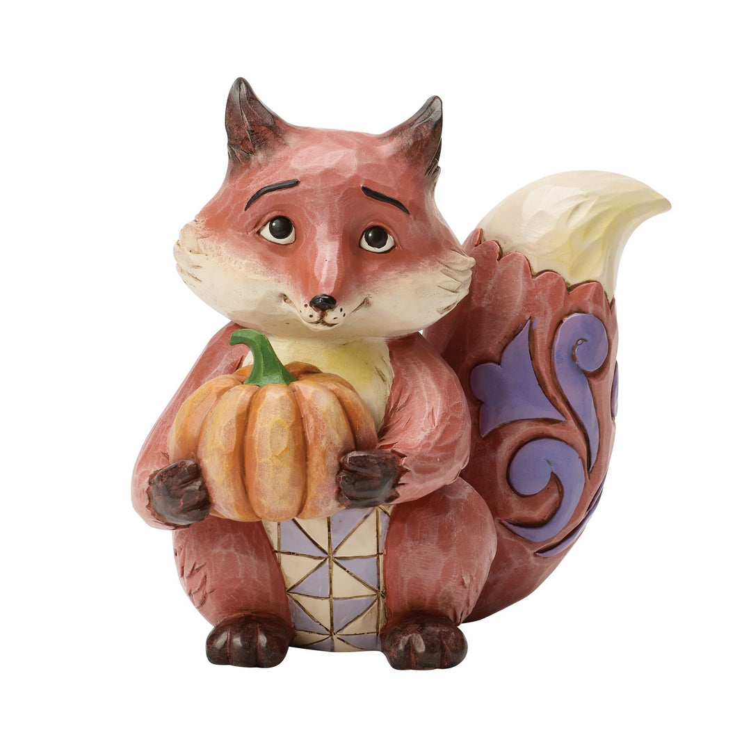 Fox figurine holding a pumpkin on a white background