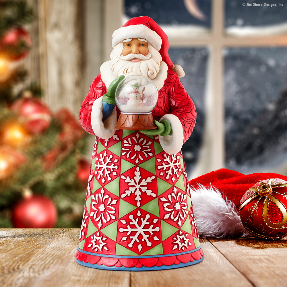 Decorative Santa figurine holding a snow globe with Christmas tree and ornaments in the background