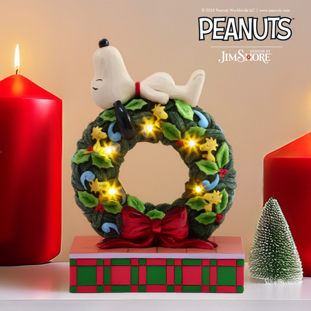 Decorative wreath with a small dog figure, surrounded by red candles and a miniature tree, featuring the Peanuts and Jim Shore logos.