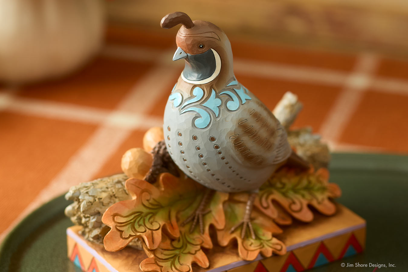 Decorative quail figurine on a ceramic base with a blurred background